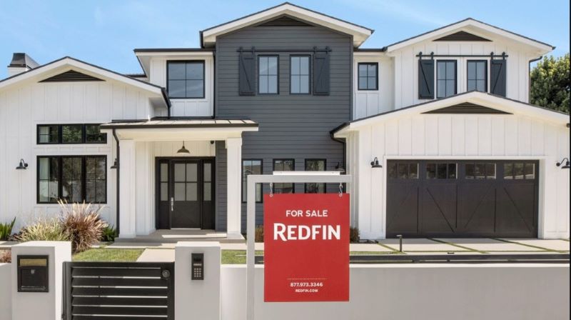 A Redfin "for sale" sign in front of a house. 