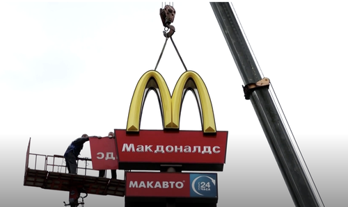 Workers use a crane to dismantle a McDonald's sign