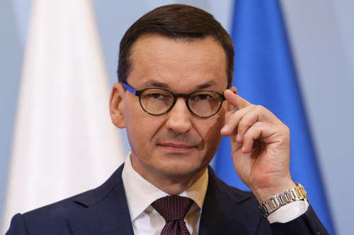 The Polish president adjusts his eyeglasses as he stares into the camera