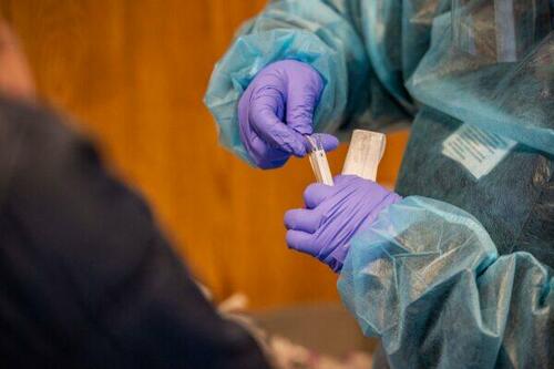 Un travailleur médical place un écouvillon nasal dans un tube à essai
